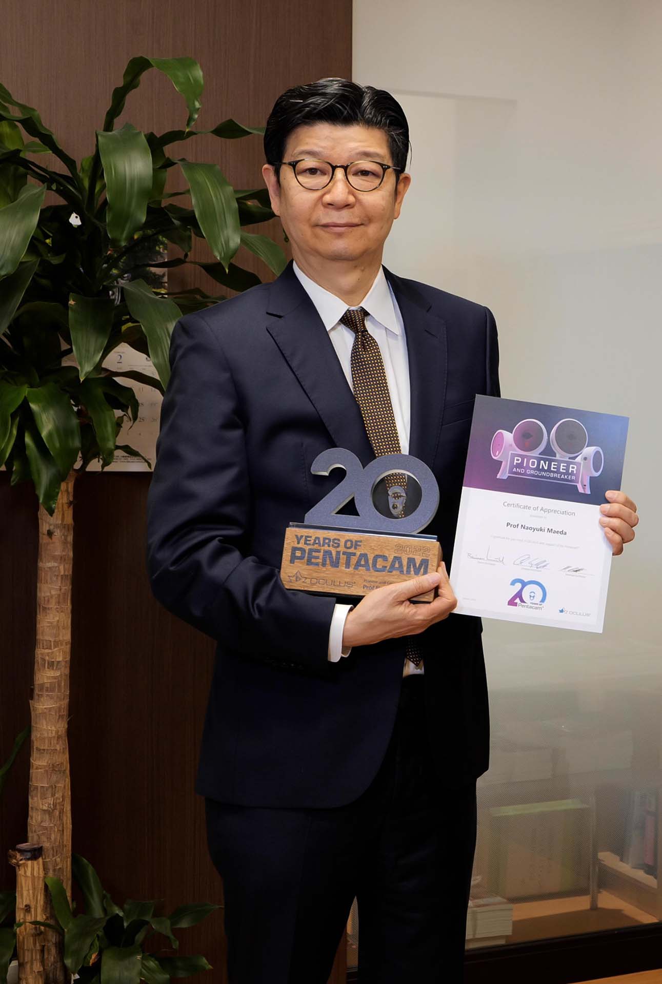 Prof Maeda Naoyuki holding the 20th Anniversary Pentacam® Trophy and the Certificate of Appreciation