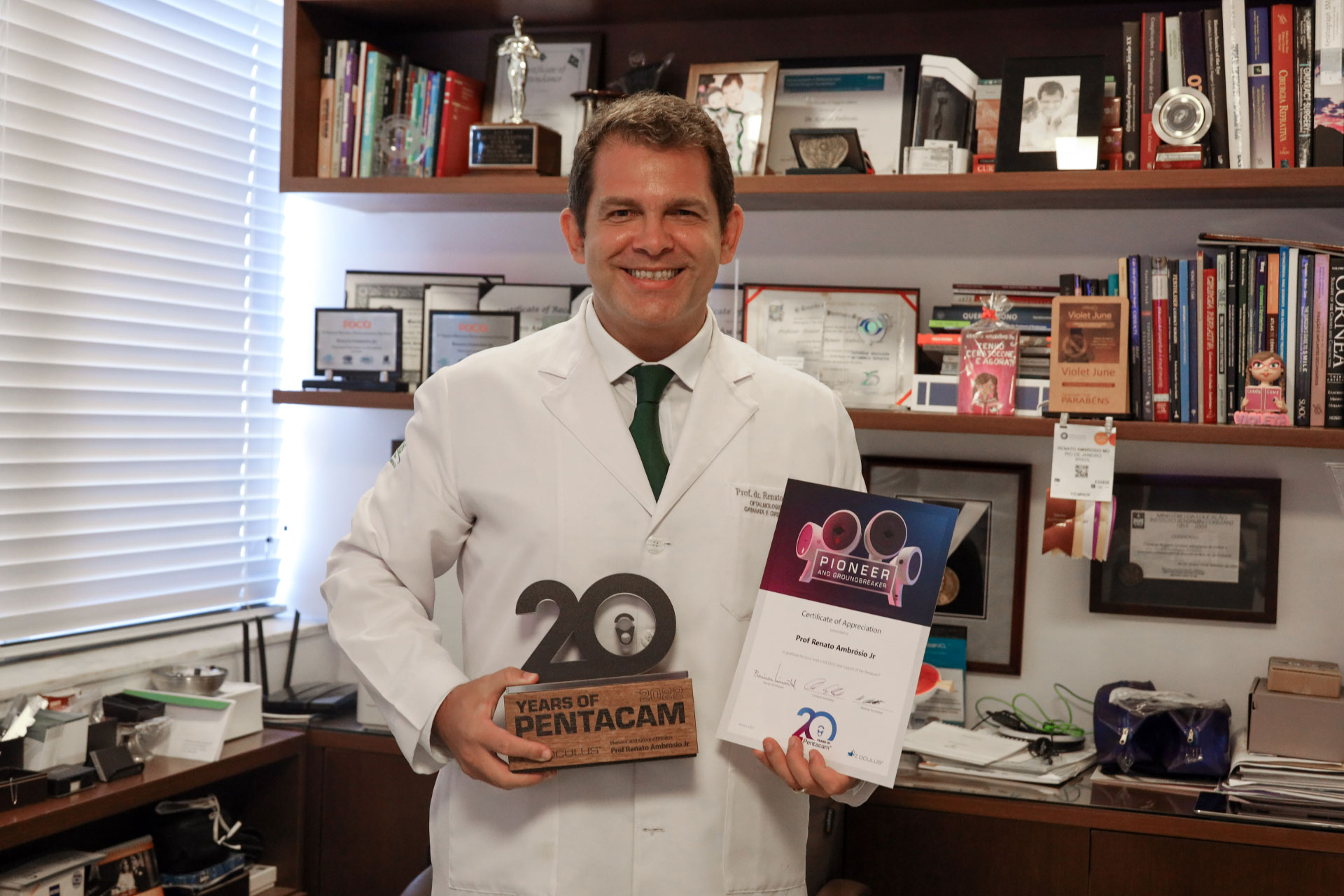 Prof Renato Ambrósio Jr. holding the 20th Anniversary Pentacam® Trophy and Certificate of Appreciation